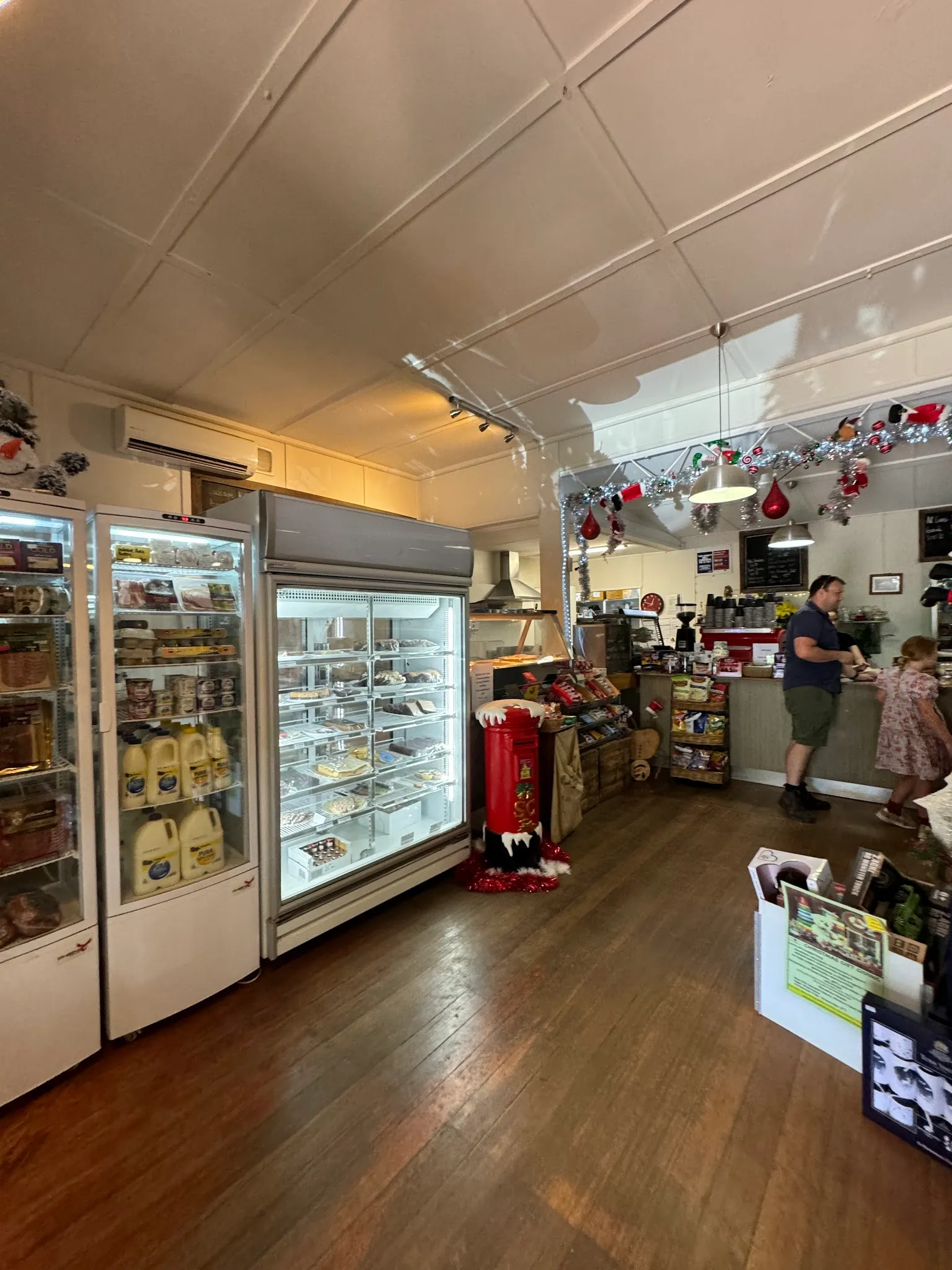 Red Hill General Store interior with refrigerated deli cabinets, timber floors, and customers at the café counter