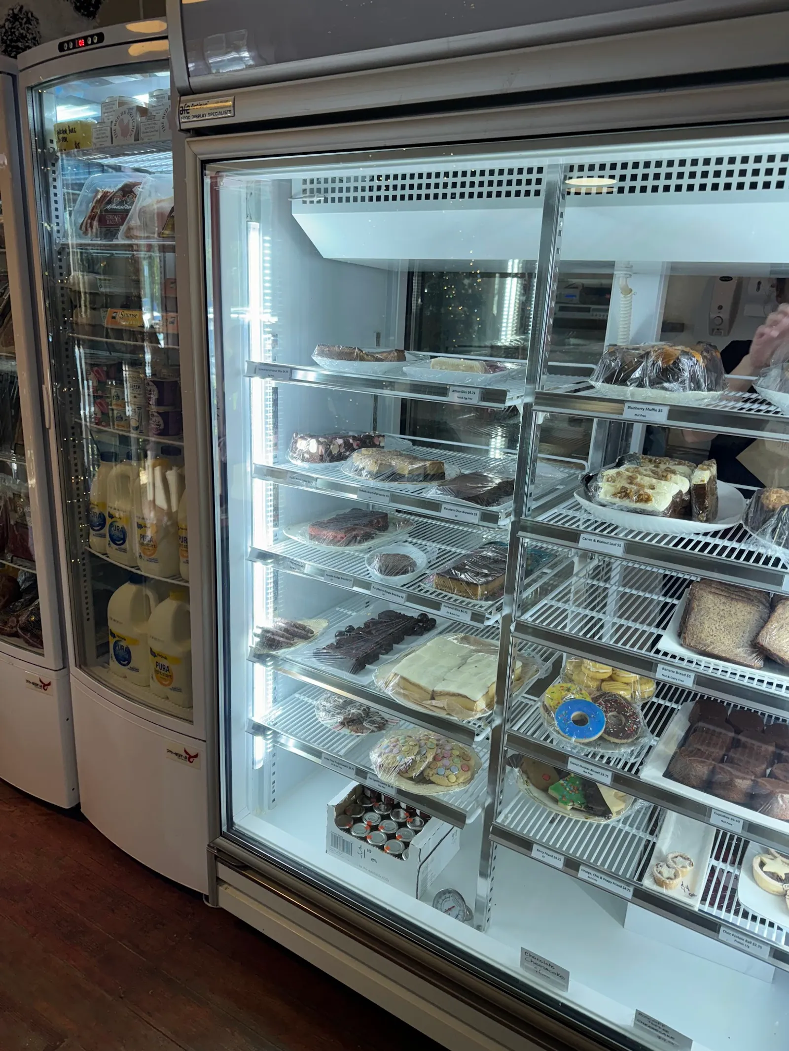 Red Hill General Store glass refrigerated baked goods cabinet with multiple shelves of cakes, slices, and pastries
